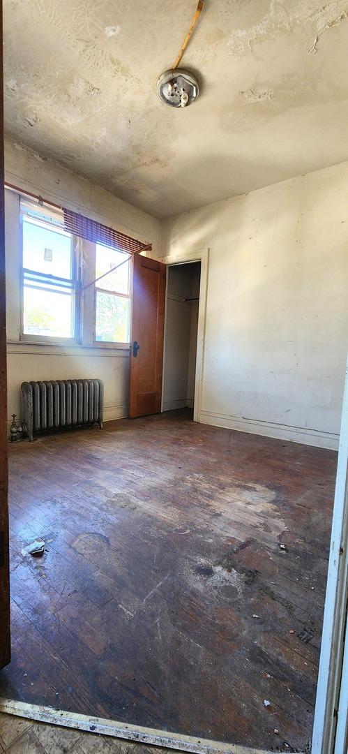 7943 S Vernon Ave, Chicago, IL 60619 - empty room with radiator heating unit, baseboards, and hardwood / wood-style floors