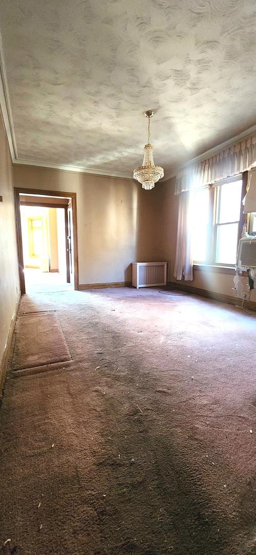 7943 S Vernon Ave, Chicago, IL 60619 - carpeted empty room with crown molding, a chandelier, and baseboards
