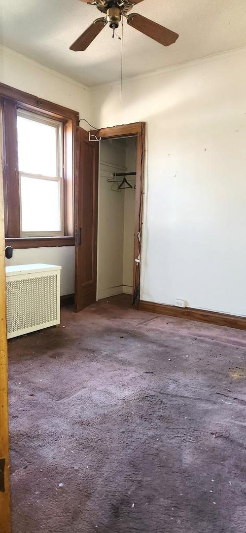 7943 S Vernon Ave, Chicago, IL 60619 - unfurnished bedroom with radiator, a ceiling fan, and baseboards