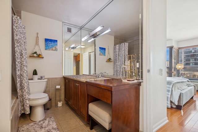 bathroom with connected bathroom, toilet, tile walls, visible vents, and vanity