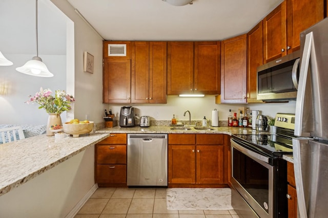 kitchen with a sink, visible vents, light stone countertops, appliances with stainless steel finishes, and light tile patterned flooring