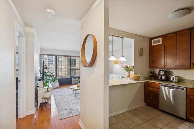 kitchen featuring light stone countertops, stainless steel dishwasher, baseboards, brown cabinetry, and visible vents