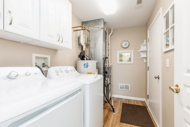 13472 Delaney Rd, Huntley, IL 60142 - laundry area featuring cabinet space, washing machine and dryer, light wood-style flooring, gas water heater, and baseboards