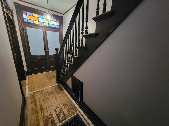 foyer entrance with stairway, ornamental molding, visible vents, and wood finished floors