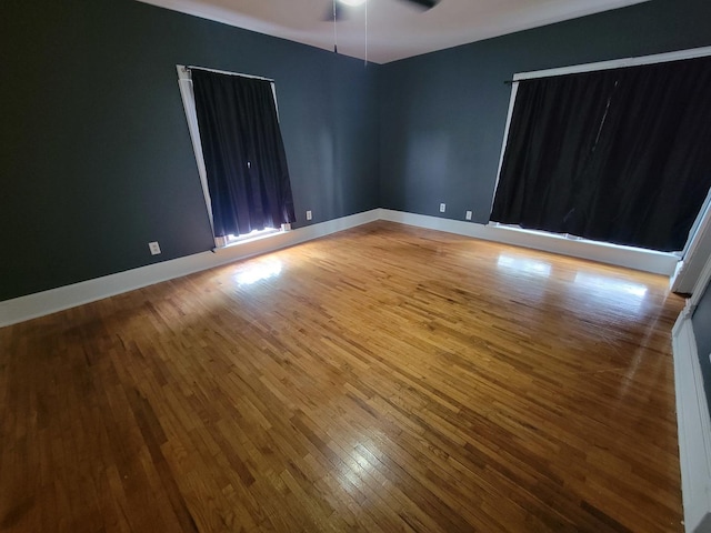 empty room with ceiling fan, baseboards, and hardwood / wood-style floors