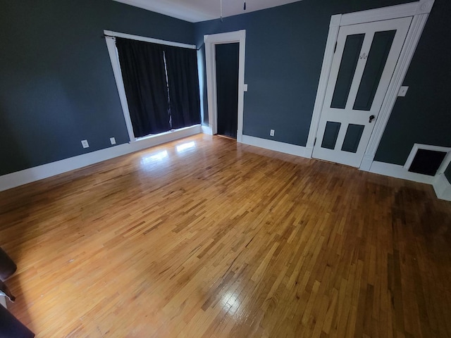 spare room featuring baseboards and wood finished floors