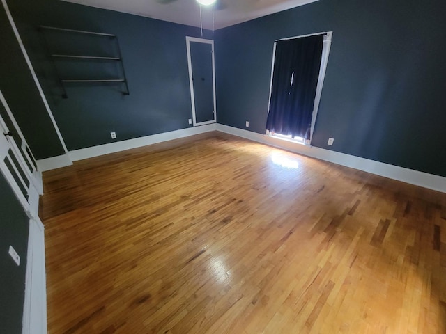 spare room with ceiling fan, baseboards, and wood finished floors
