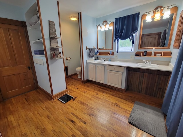full bathroom with toilet, hardwood / wood-style floors, double vanity, and a sink