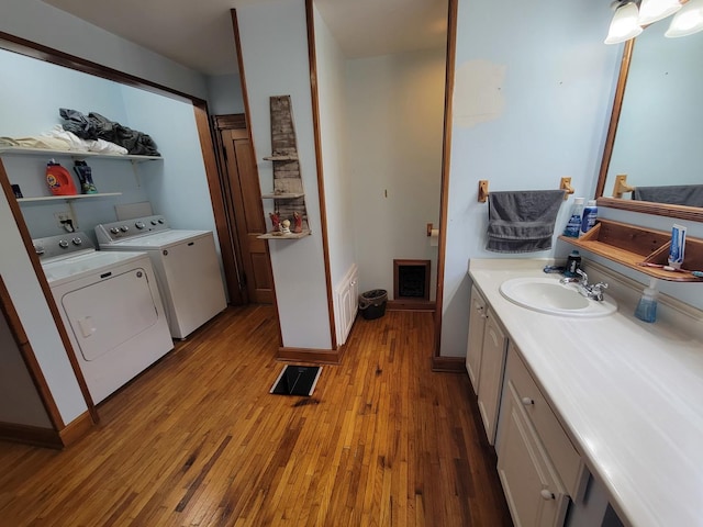 bathroom featuring washing machine and clothes dryer, visible vents, vanity, and hardwood / wood-style flooring