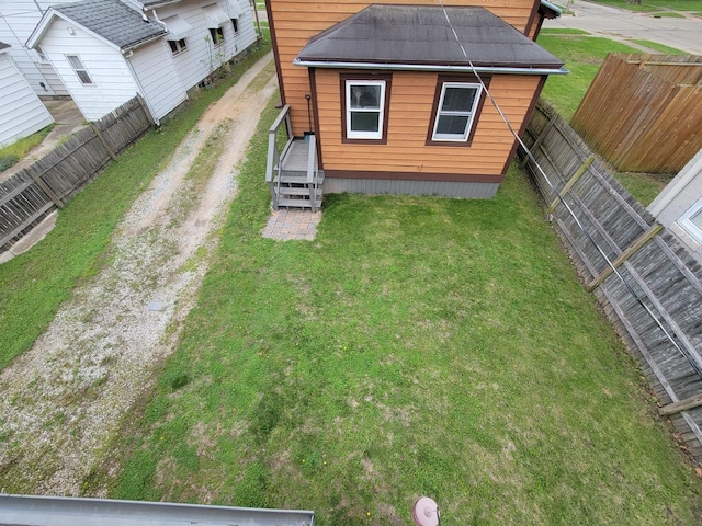 exterior space featuring dirt driveway, a yard, and a fenced backyard
