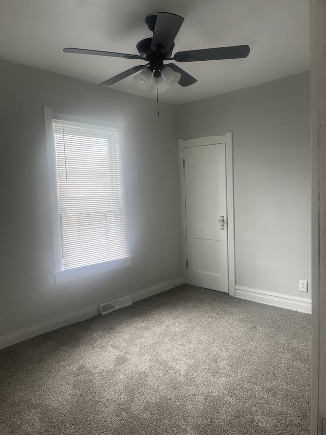carpeted spare room featuring ceiling fan and baseboards