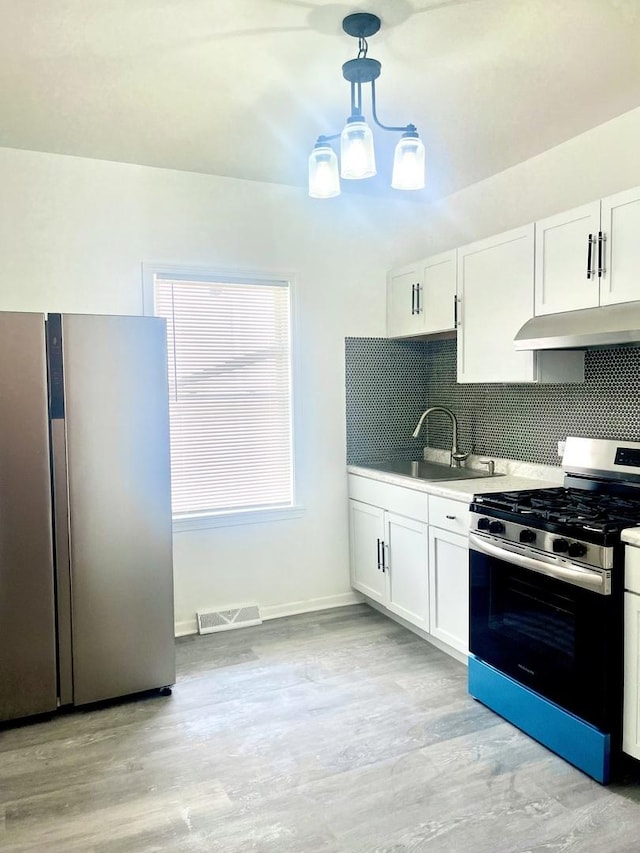 kitchen featuring appliances with stainless steel finishes, under cabinet range hood, visible vents, backsplash, and light wood-type flooring