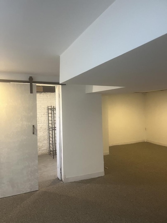 finished below grade area featuring a barn door and carpet