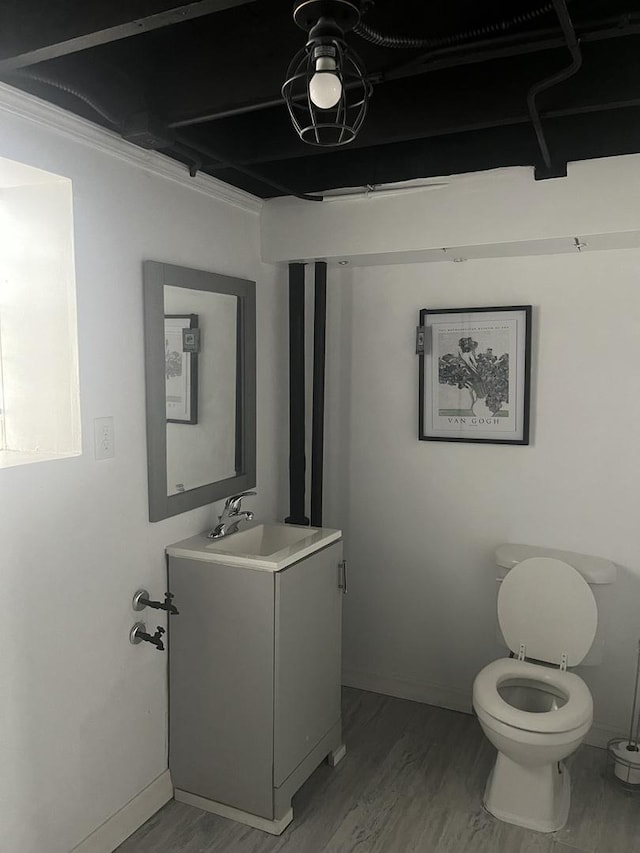 bathroom featuring toilet, vanity, wood finished floors, and baseboards