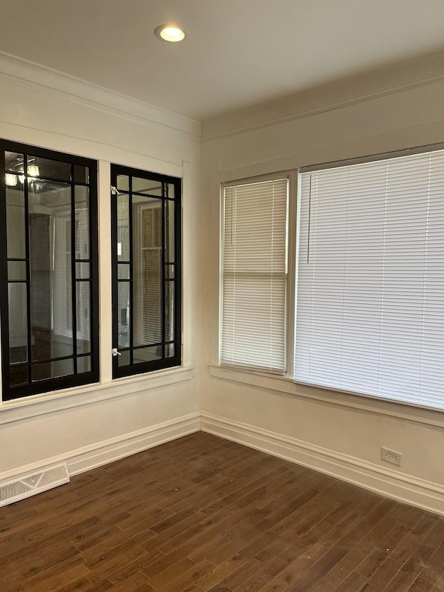 spare room with crown molding, dark wood finished floors, visible vents, baseboards, and recessed lighting