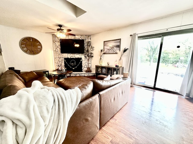 1310 E 15th Rd, Streator, IL 61364 - living room featuring a stone fireplace, a ceiling fan, visible vents, and wood finished floors