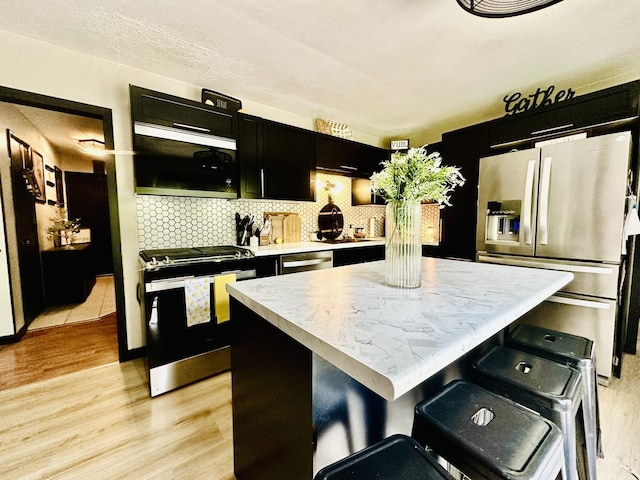 1310 E 15th Rd, Streator, IL 61364 - kitchen with light wood-style floors, stainless steel appliances, dark cabinets, and a center island
