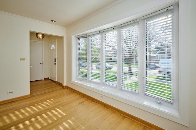 foyer with baseboards, light wood-style flooring, and ornamental molding