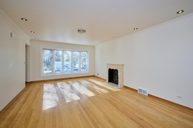 unfurnished living room with crown molding, visible vents, light wood-style flooring, and baseboards