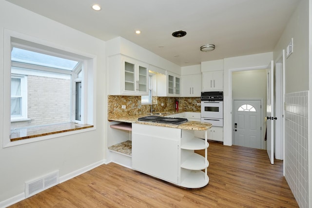 kitchen featuring oven, open shelves, visible vents, a warming drawer, and white cabinetry