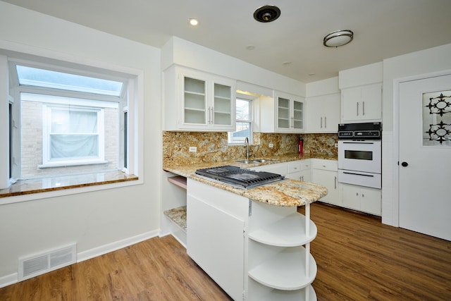 kitchen with a sink, oven, open shelves, visible vents, and a warming drawer