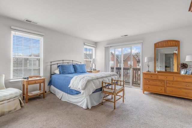 bedroom with light colored carpet, visible vents, and access to outside