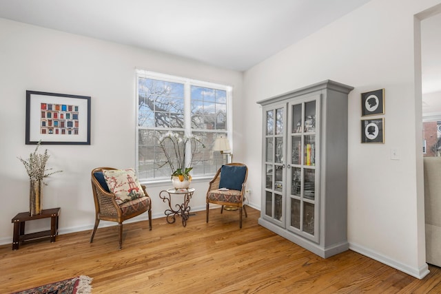 sitting room with baseboards and light wood-style flooring