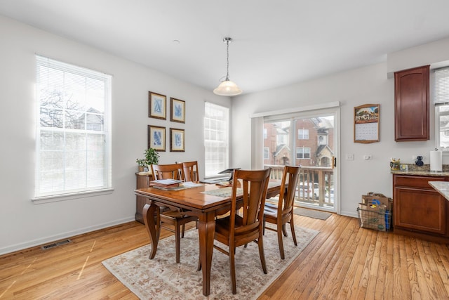 dining room with light wood-type flooring, visible vents, and baseboards
