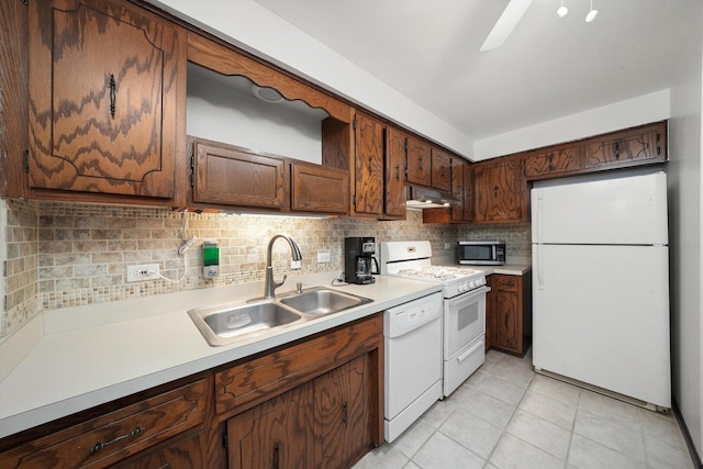 kitchen with a sink, white appliances, backsplash, under cabinet range hood, and light countertops