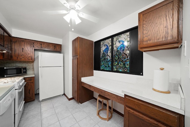 kitchen with a ceiling fan, white appliances, built in desk, and light countertops