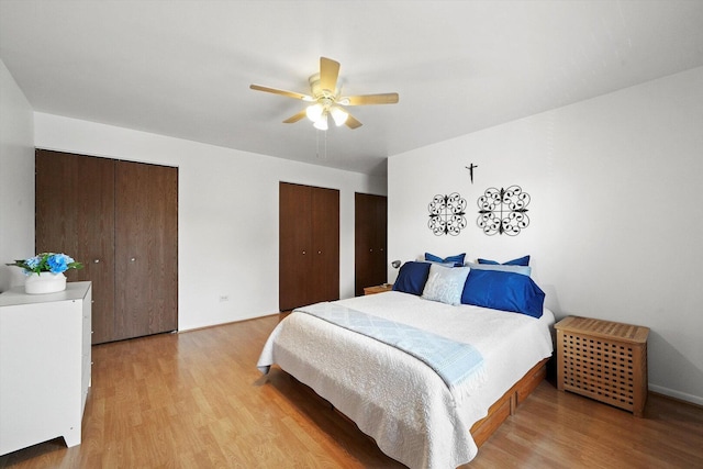 bedroom featuring a ceiling fan, light wood-type flooring, and two closets