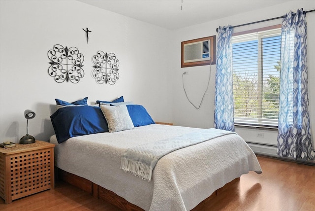 bedroom with a wall mounted air conditioner and wood finished floors