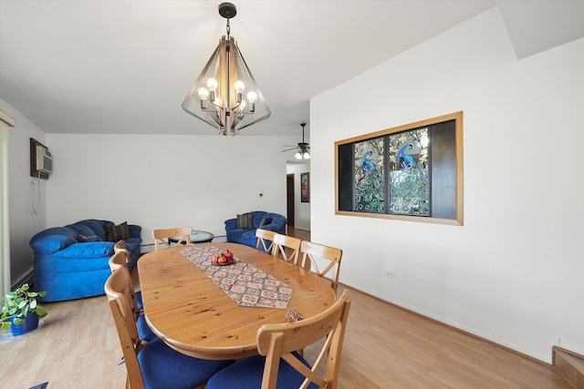 dining area with baseboards, light wood-style flooring, ceiling fan with notable chandelier, and a wall unit AC