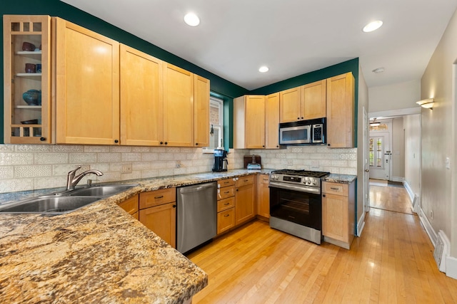 kitchen featuring appliances with stainless steel finishes, a sink, light brown cabinets, tasteful backsplash, and recessed lighting