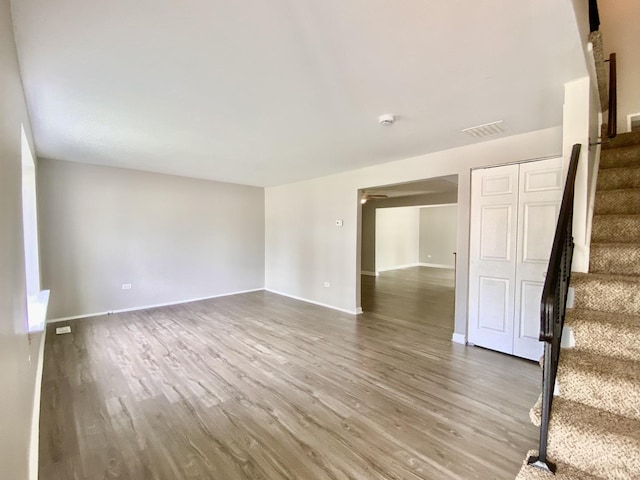 empty room featuring stairway, wood finished floors, and baseboards