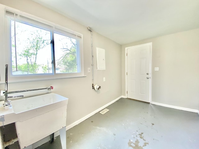 clothes washing area featuring baseboards, healthy amount of natural light, and a sink
