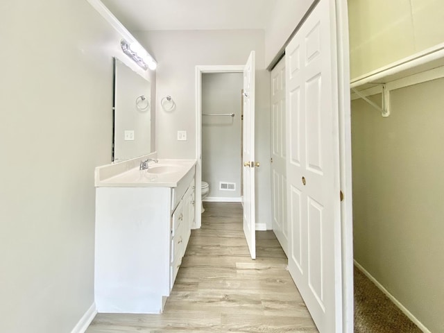 bathroom featuring toilet, vanity, wood finished floors, and baseboards