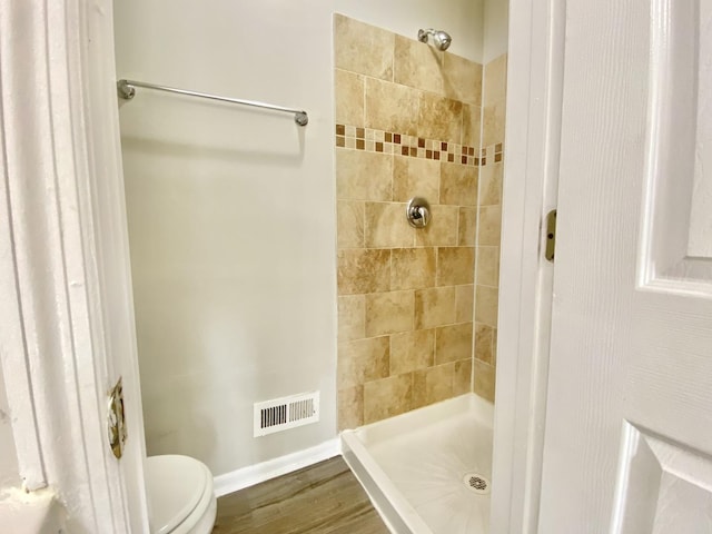 bathroom with a shower stall, toilet, and wood finished floors