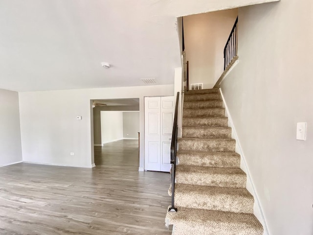 staircase featuring wood finished floors and baseboards
