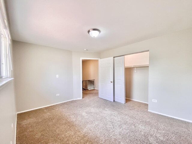 unfurnished bedroom featuring light colored carpet, baseboards, and a closet