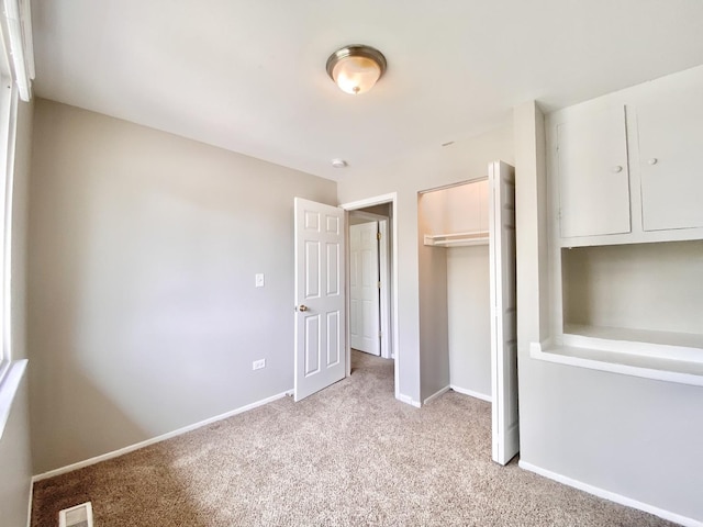 unfurnished bedroom with light carpet, a closet, and baseboards