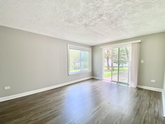 unfurnished room with dark wood finished floors, baseboards, plenty of natural light, and a textured ceiling