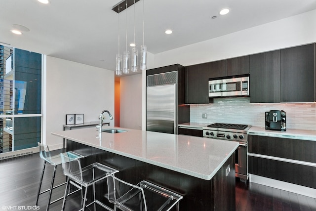 kitchen featuring dark wood-type flooring, a sink, a kitchen island with sink, and high quality appliances