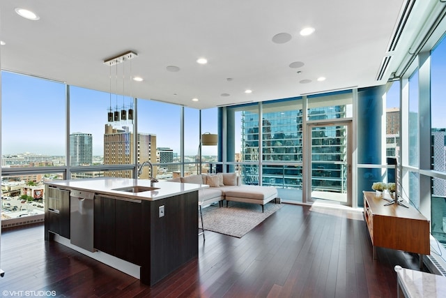 interior space with a view of city, dark wood-style flooring, a wall of windows, an island with sink, and a sink