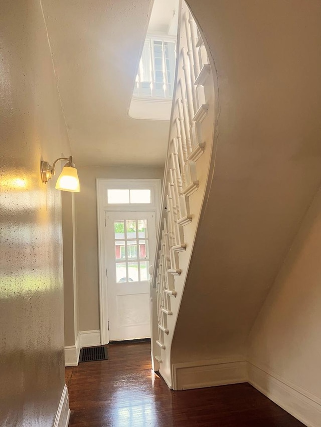 doorway featuring baseboards, visible vents, wood finished floors, and stairway