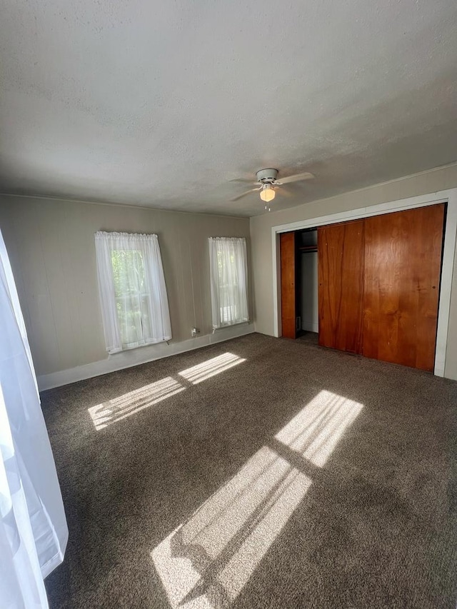 unfurnished bedroom featuring a closet, baseboards, ceiling fan, a textured ceiling, and carpet flooring