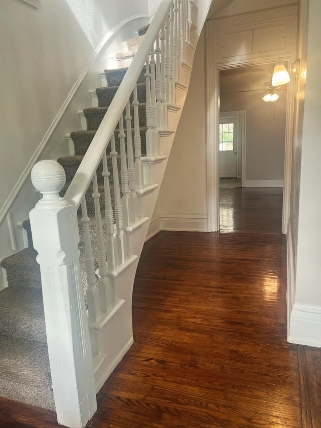 staircase with baseboards, ceiling fan, and hardwood / wood-style flooring