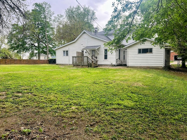 back of property with a lawn and fence
