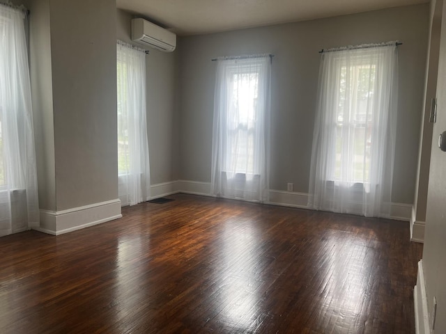 unfurnished room with baseboards, wood finished floors, and a wall mounted air conditioner