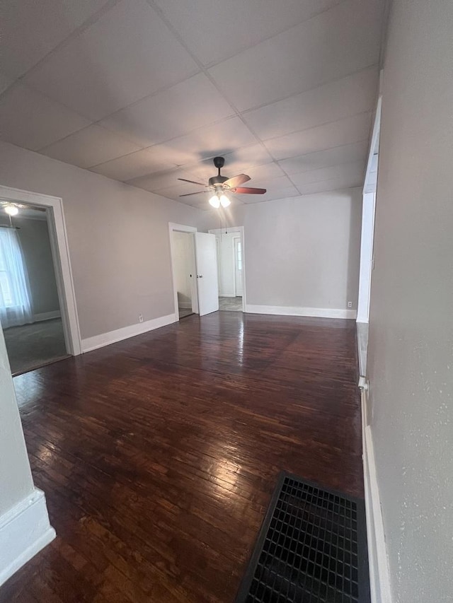spare room with wood-type flooring, a ceiling fan, and baseboards